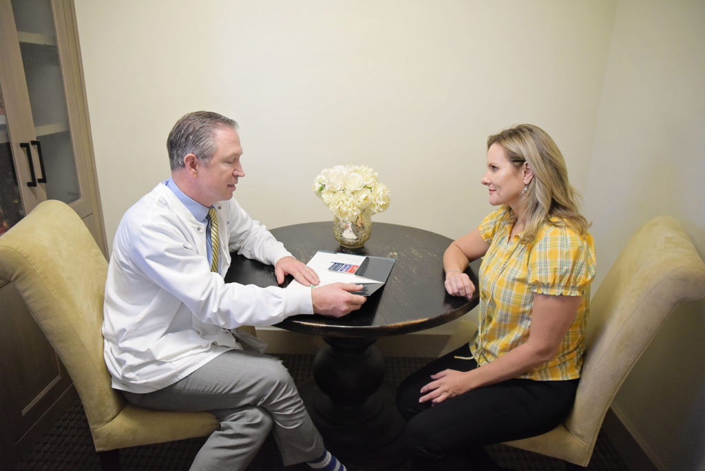 Periodontist Dr. Warren consults with a patient about options available to help her with gum disease treatment.
