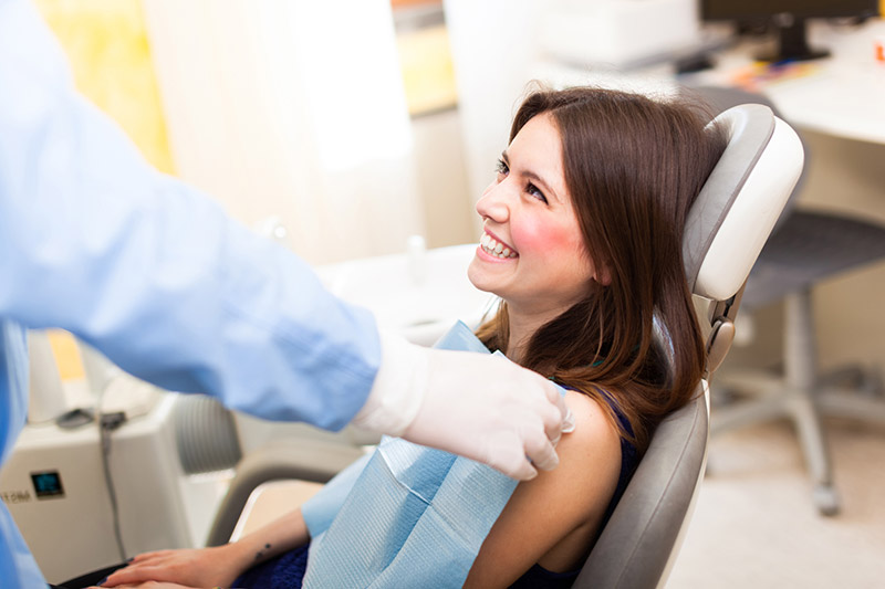 Smiling patient in dental chair beside dentist